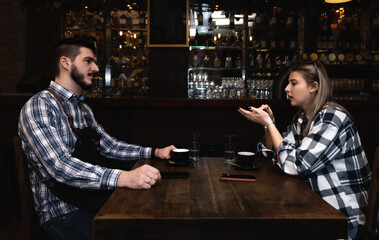 Confident owner of cafe interviewing young specialist. Manager of cafeteria or coffee shop job interview with young male bartender barista or waiter applied for work in the restaurant. Employee hiring