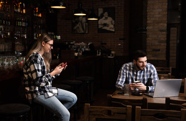 Millennial hipsters husband and wife owners of cafe bar restaurant sitting in the evening after closing talking checking profit, sales calculating order for the next day and resting after a busy day