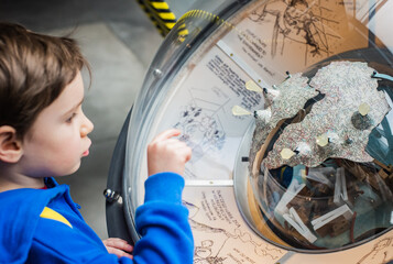 Zaciekawiony chłopiec w Centrum Nauki Kopernik ogląda i poznaje eksponaty. Wiedza, edukacja dzieci. © malgo_walko
