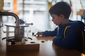 Five year old cute boy in science world carefully observing exponents in museum. Curiosity and children's knowledge concept.