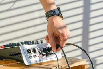 closeup of male hand connecting a cable to a sound mixer controller