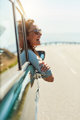 Feeling free on the open road. Cropped shot of an attractive woman hanging out of a car window...