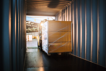 Photo inside contrainer while warehouse worker driving forklift for loading pallets into container