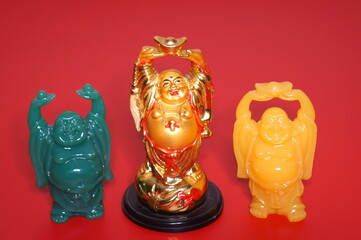Three Buddha figurines on a red background.