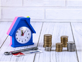 Money for real estate, home loan concept. Coins, credit card, an apartment key, alarm clock in the...