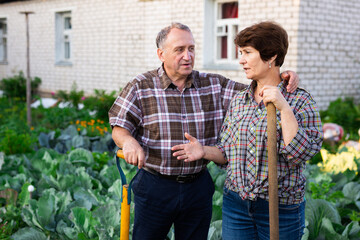 mature Man and woman gardeners with shovels while gardening