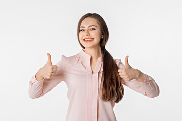 Portrait of confident brunette woman showing thumbs up in approval, recommending, like smth good, standing over white background with a happy smile on face