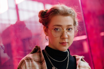 portrait of young hipster girl against pink glass background
