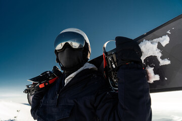 Hobby snowboarding in a helmet and glasses in winter gear, going to conquer the top of the mountain on a snowboard.