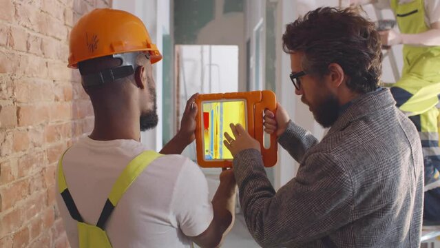 Engineer and foreman use thermal imager on tablet at construction site. Realtime