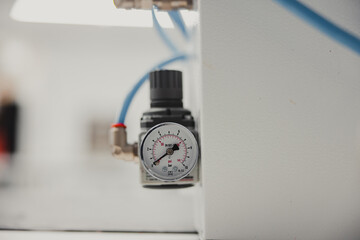 Close-up of a pressure gauge on a white wall in a factory