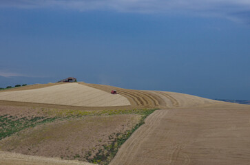 Fototapeta na wymiar Glimpse of the Molise countryside while an agricultural machine is harvesting the wheat