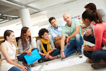Dynamic designers. A group of multi-ethnic creatives huddled together and listening to the...