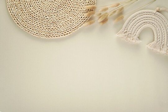 Aesthetic bohemian style background with space for text or product, flat lay composition with bunny tail grass, wicker table mat, macrame rainbow.
