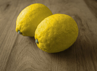 Two Fresh Yellow Lemons on a Wooden Surface Under Soft Lighting