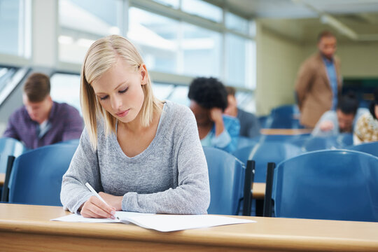 The Last Exam Before The Real World Begins. Shot Of A Group Of University Students Sitting In A Lecture.