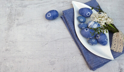 Weisse Servierplatte mit blauen Ostereiern auf hellen schäbigen Holz mit Platz für Text.