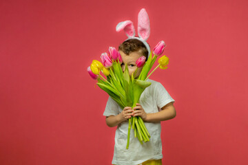 Happy Easter. A child in a rabbit costume holds a bouquet of yellow and pink tulips. A charming...