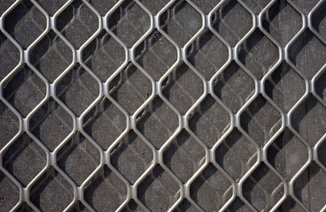 A large-meshed metal grid in front of a fine metal grid. Silver metal background.