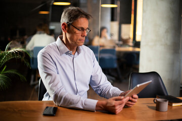 Fototapeta premium Portrait of businessman in office. Man using digital tablet. Businessman having video call..