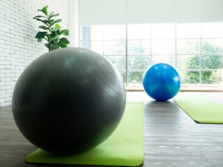 Trainer prepare elastic ball exercise black and blue color on green yoga mat before trainee go to the class room
