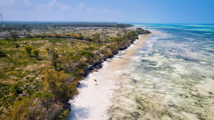 The aerial view of Zanzibar's Indian Ocean coastline is simply stunning, featuring palm trees, white sand, and sparkling blue waters. With luxurious hotels and a tropical landscape, it is the perfect 