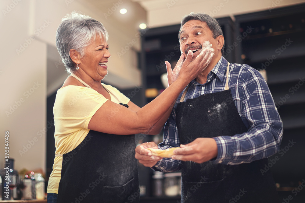 Poster clowning around in the kitchen. shot of a mature couple cooking together at home.