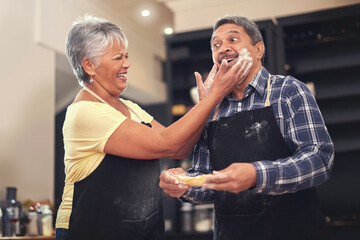 Clowning around in the kitchen. Shot of a mature couple cooking together at home.