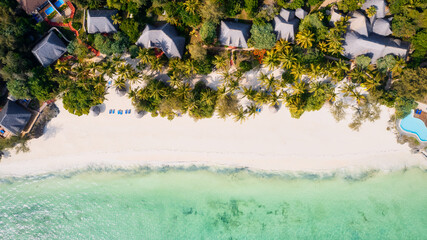 Fototapeta na wymiar From above, the stunning beauty of Zanzibar's Nungwi Beach is captured in an aerial view with a yacht and palm trees on the sandy beach.