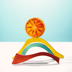 stylized landscape, a sun made with a red orange slice over a  rainbow made with colored wooden shapes