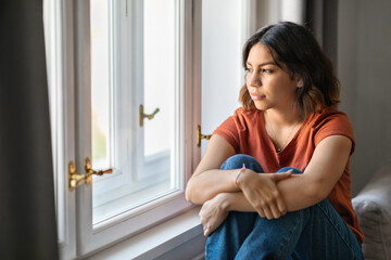 Portrait Of Pensive Young Middle Eastern Woman Sitting Near Window At Home