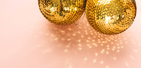 Gold shiny balls with sequins on a pink background.