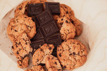 Oatmeal chocolate chip cookies and chocolate chips on parchment paper.