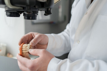 dental technician look at prosthesis under a microscope in a lab