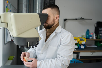 Naklejka na ściany i meble Dental technician looking in microscope check a work in a lab.