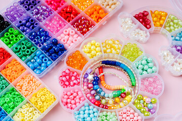 Kids handmade beaded jewelry and different multi-colored beads for children's needlework and crafts in boxes. DIY art activity for kids. Motor skills, creativity and  hobby.