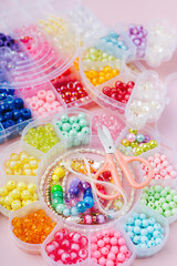 Kids handmade beaded jewelry and different multi-colored beads for children's needlework and crafts in boxes. DIY art activity for kids. Motor skills, creativity and  hobby.