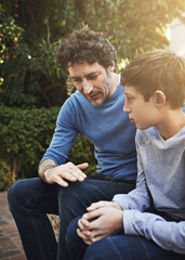 Dad knows best. Shot of a father and son having a heart to heart in the backyard.