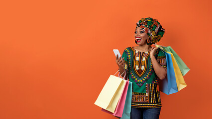 Fototapeta premium Emotional black woman in african costume shopping online, copy space