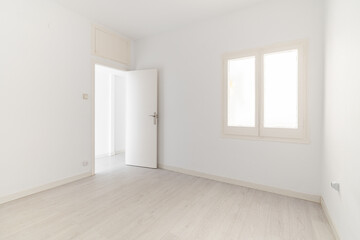 View of an empty white bright room with window without furniture after painting and renovation with wooden floor and baseboards. Concept of beautiful laconic interior for various inspiring ideas
