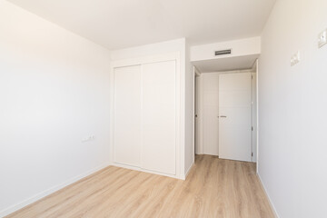 White empty sunny room with built-in wardrobe ventilation and two doors to the bathroom and exit. Concept of a new building or real estate for rent