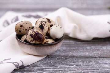 Quail eggs in a bowl on a dark gray old wooden table. Copy space