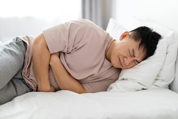 Man lying in bed and suffering from stomach pain
