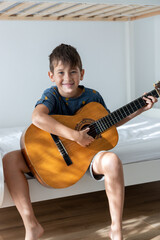 Boy with acoustic guitar in his room.