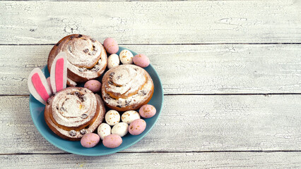 Easter eggs and decor on fresh buns with spirals with white icing sugar.