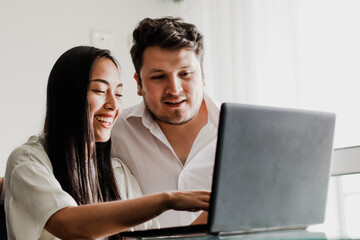 Photo of young couple looking at a web page on a laptop, planning something, shopping, etc. Concept of lifestyle, human relations, internet. © artrolopzimages