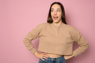 Young excited happy woman with open mouth standing isolated over pink background.