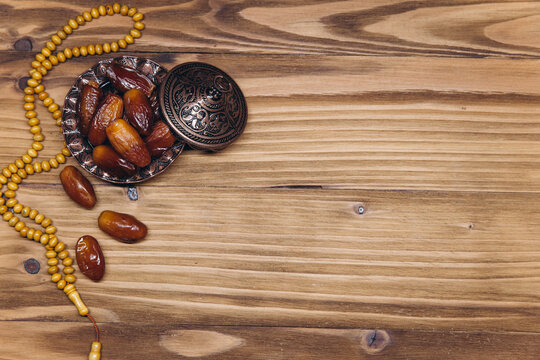 Table top view image of decoration Ramadan Kareem, dates fruit and rosary beads on wooden background. Flat lay with copy space.