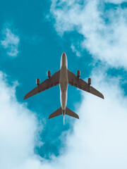 Aeroplane in flight beneath a blue sky with clouds, low flying plane, airbus aircraft - obrazy, fototapety, plakaty