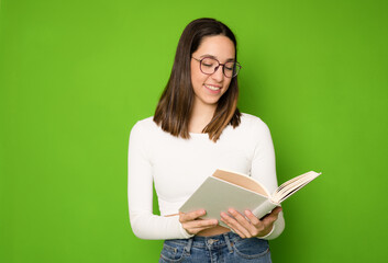 beautiful young woman in glasses with a book in her hands isolated over green background.